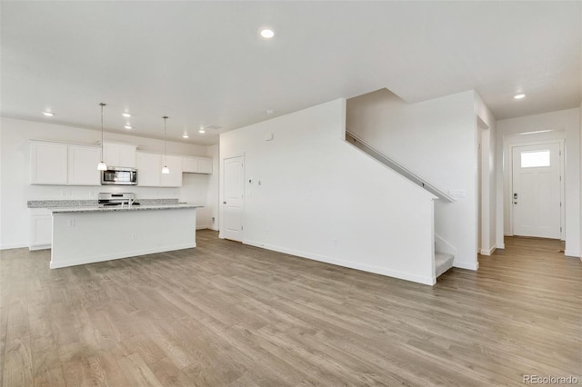 unfurnished living room featuring recessed lighting, light wood-style floors, baseboards, and stairs