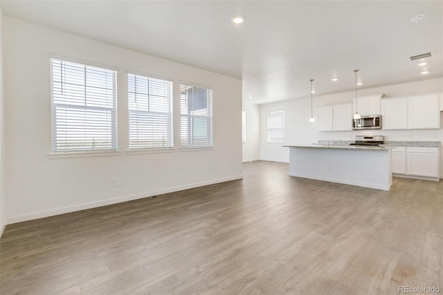 unfurnished living room with light wood-style floors, recessed lighting, baseboards, and a sink