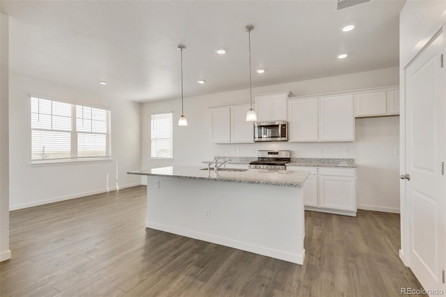 kitchen featuring appliances with stainless steel finishes, white cabinets, wood finished floors, baseboards, and recessed lighting