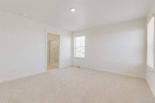 empty room featuring light colored carpet and baseboards