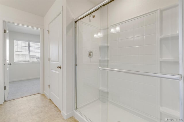 full bathroom with a shower stall and baseboards