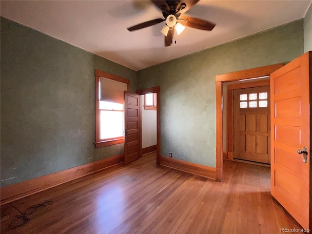 empty room featuring ceiling fan, a healthy amount of sunlight, and light wood-type flooring