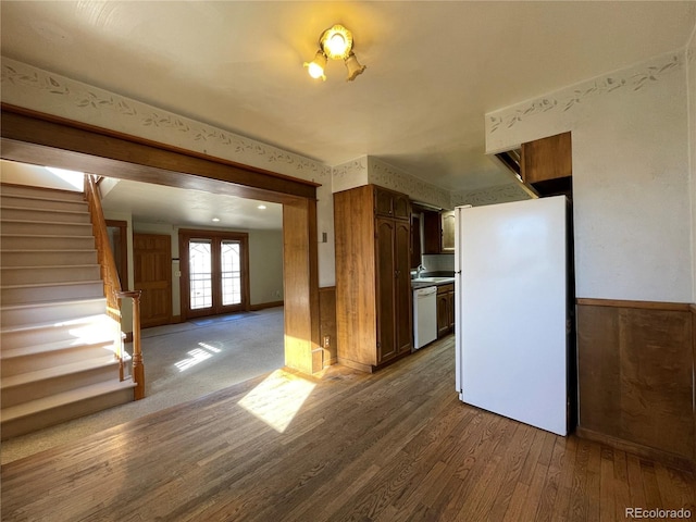 kitchen with french doors, sink, wood walls, white appliances, and hardwood / wood-style floors