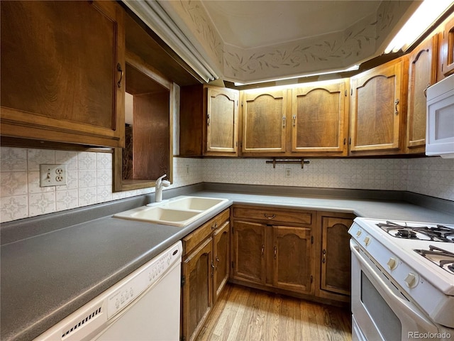 kitchen with white appliances, sink, light hardwood / wood-style flooring, and backsplash