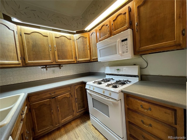 kitchen featuring backsplash, white appliances, sink, and light wood-type flooring