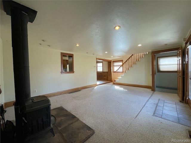 carpeted living room featuring a textured ceiling and a wood stove