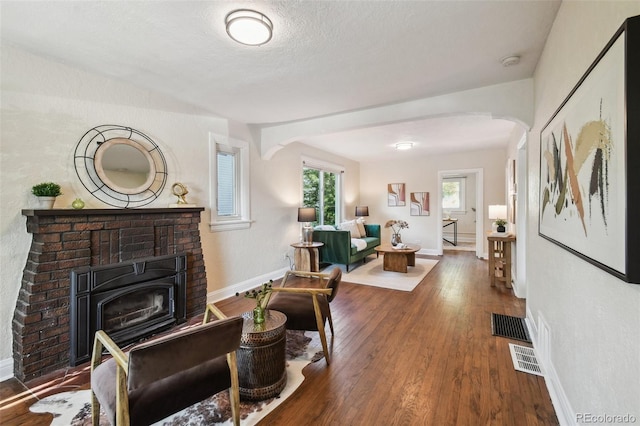 1633 Gaylord St, Denver, CO 80206 - living area featuring arched walkways, a brick fireplace, wood finished floors, and baseboards