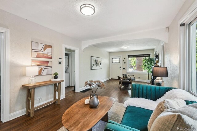 1633 Gaylord St, Denver, CO 80206 - living area featuring arched walkways, wood finished floors, stacked washing machine and dryer, and baseboards