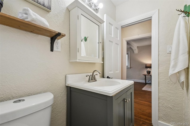 1633 Gaylord St, Denver, CO 80206 - bathroom with wood finished floors, toilet, vanity, a textured wall, and baseboards