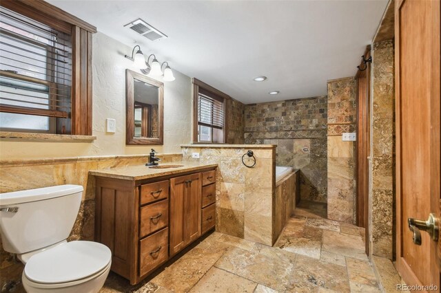 1633 Gaylord St, Denver, CO 80206 - full bathroom featuring tile walls, stone tile floors, toilet, vanity, and recessed lighting