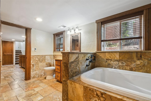 1633 Gaylord St, Denver, CO 80206 - full bath with stone tile flooring, tile walls, a wainscoted wall, a bath, and toilet