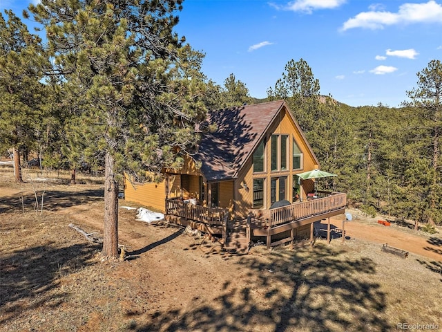 back of house featuring a wooden deck and a wooded view