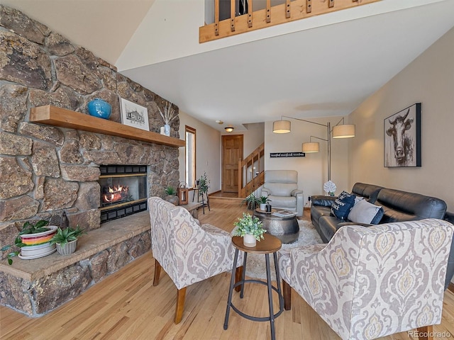 living room featuring stairway, lofted ceiling, wood finished floors, and a fireplace