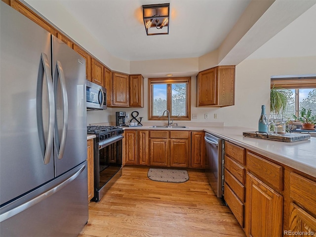 kitchen featuring a sink, appliances with stainless steel finishes, brown cabinetry, and light countertops