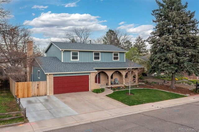 traditional-style home featuring a porch, a front yard, roof with shingles, fence, and concrete driveway
