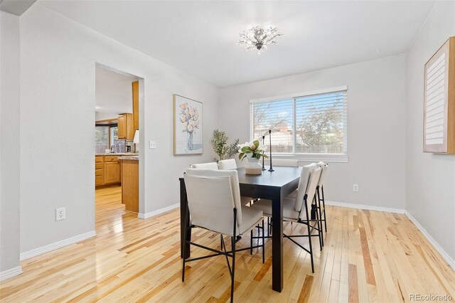 dining area with baseboards and light wood finished floors