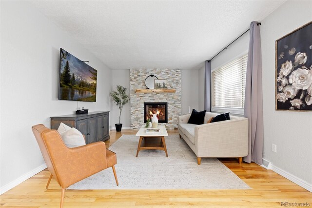 living area with baseboards, wood finished floors, and a fireplace