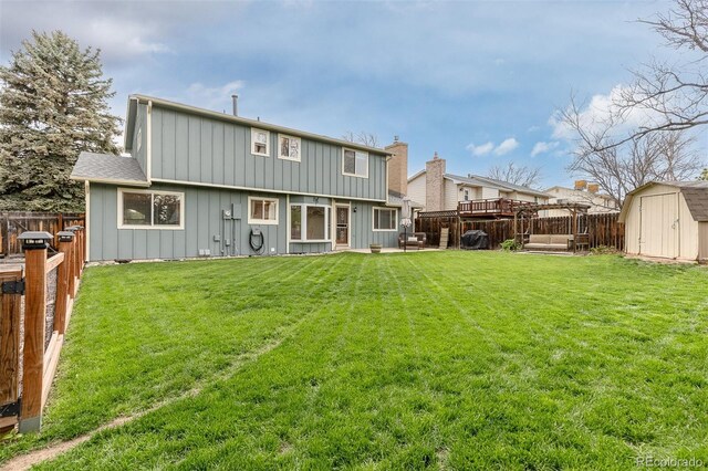 back of house with a storage unit, board and batten siding, a fenced backyard, a lawn, and an outdoor structure