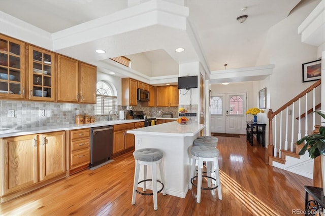 kitchen with a center island, sink, range with electric cooktop, dishwashing machine, and a kitchen bar