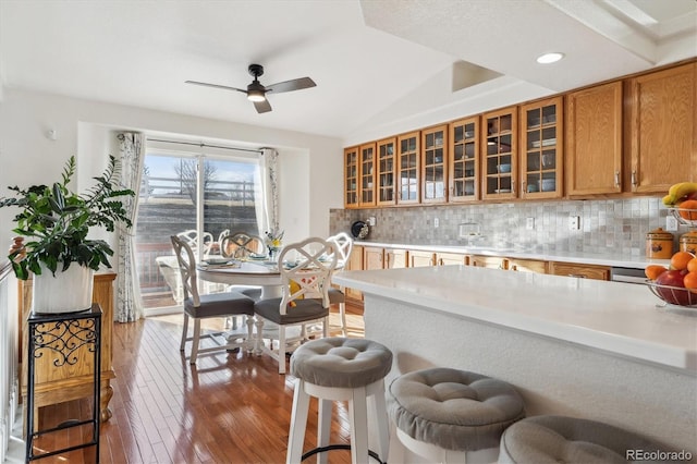 kitchen with a breakfast bar, lofted ceiling, dark wood-type flooring, ceiling fan, and tasteful backsplash