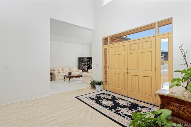 foyer featuring a wealth of natural light, a towering ceiling, and baseboards