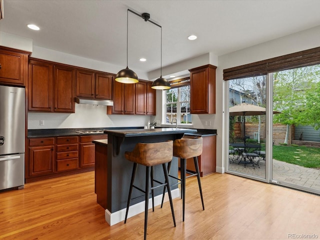 2880 Emporia Ct, Denver, CO 80238 - kitchen with freestanding refrigerator, dark countertops, a breakfast bar area, light wood-style flooring, and recessed lighting