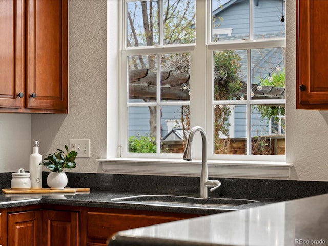 2880 Emporia Ct, Denver, CO 80238 - kitchen view of a textured wall, a sink, brown cabinetry, and dark stone counters