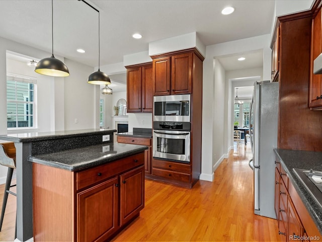 2880 Emporia Ct, Denver, CO 80238 - kitchen featuring stainless steel appliances, light wood-type flooring, a breakfast bar, decorative light fixtures, and baseboards