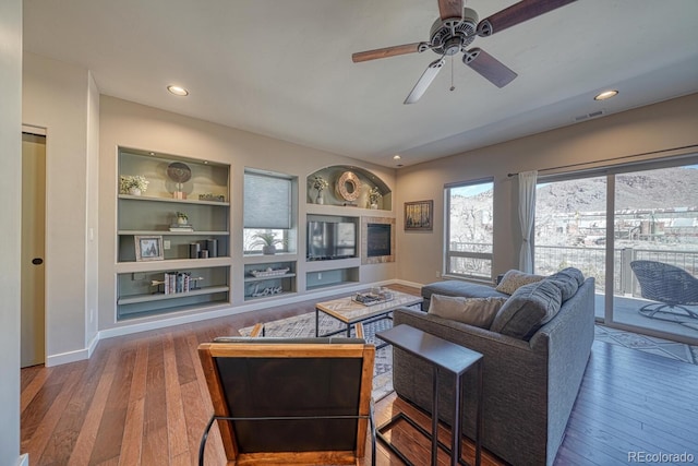 living room featuring built in features, baseboards, visible vents, and wood-type flooring