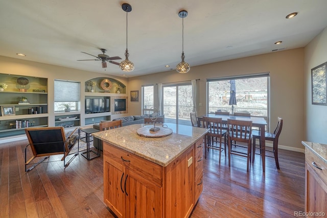 kitchen with light stone counters, visible vents, built in shelves, and dark wood-type flooring