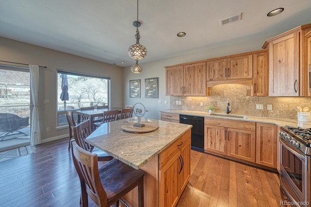 kitchen with visible vents, a sink, light stone countertops, dishwasher, and stainless steel range with gas stovetop