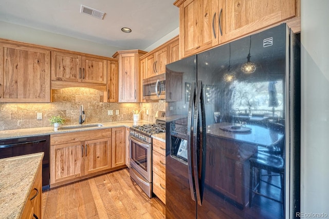 kitchen with visible vents, backsplash, light wood-style floors, black appliances, and a sink