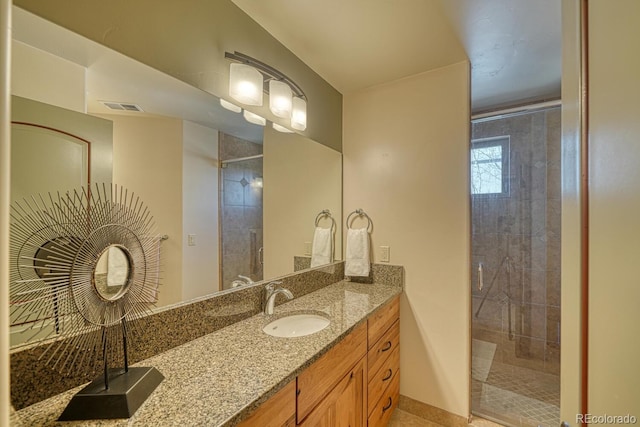 bathroom featuring vanity, visible vents, and tiled shower