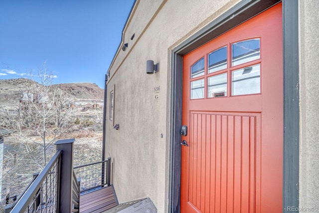 view of exterior entry featuring a mountain view, a balcony, and stucco siding