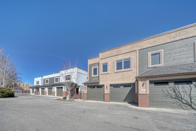 view of front of property featuring an attached garage, brick siding, and stucco siding