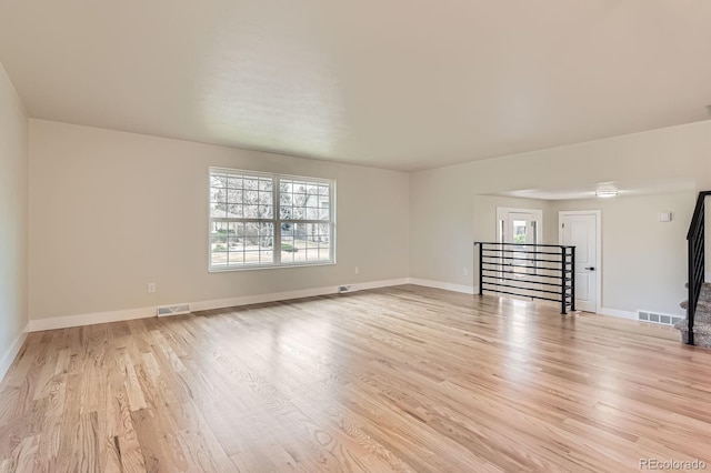 unfurnished room with light wood finished floors, visible vents, and baseboards