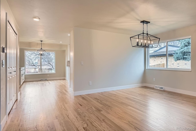 unfurnished dining area with an inviting chandelier, visible vents, and a wealth of natural light