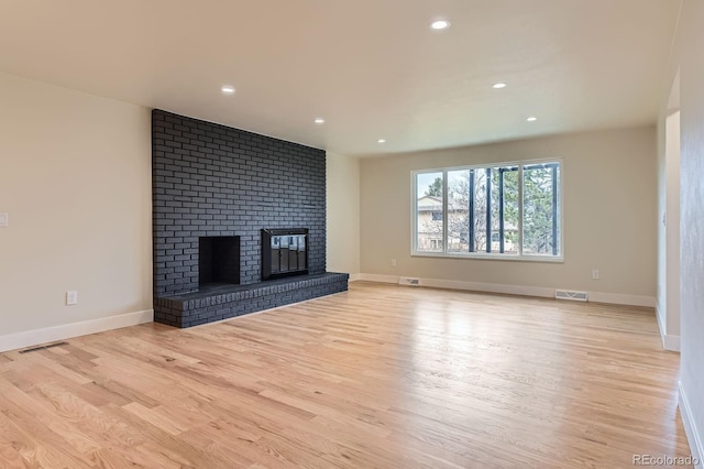 unfurnished living room with a brick fireplace, visible vents, wood finished floors, and recessed lighting