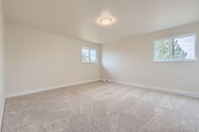 spare room featuring light carpet, baseboards, and visible vents