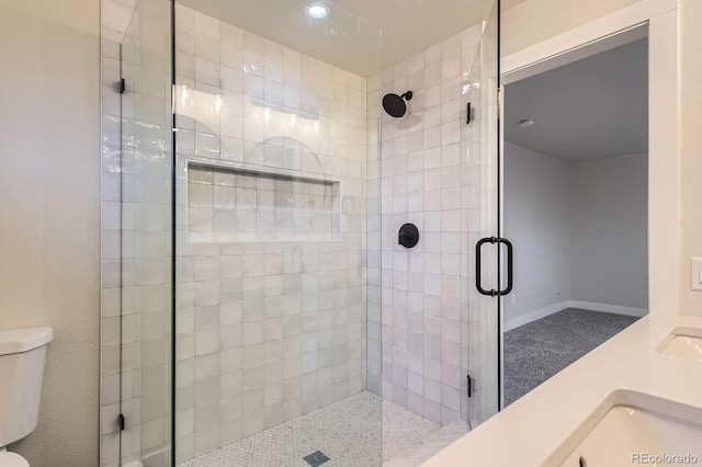 bathroom featuring toilet, a stall shower, and baseboards