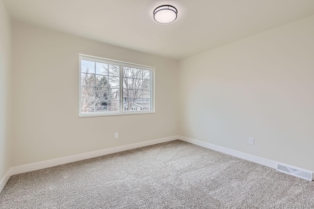 carpeted spare room with visible vents and baseboards