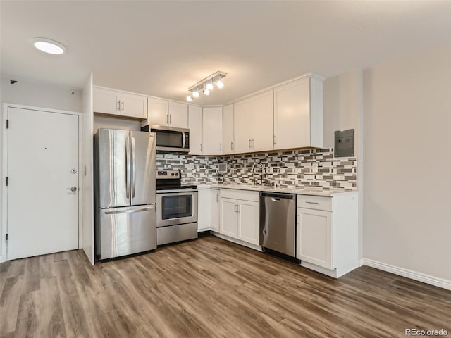 kitchen with white cabinetry, sink, tasteful backsplash, appliances with stainless steel finishes, and hardwood / wood-style flooring