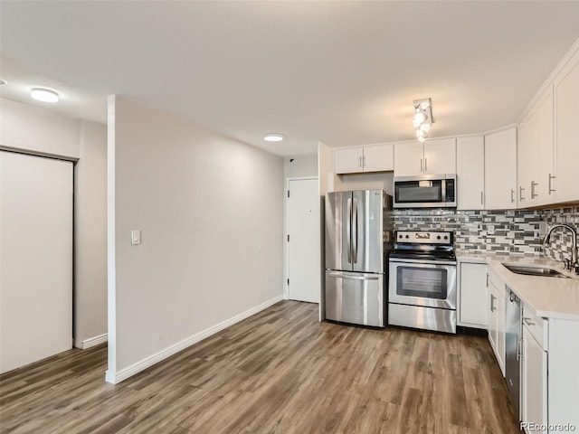 kitchen featuring sink, stainless steel appliances, tasteful backsplash, wood-type flooring, and white cabinets