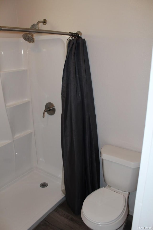 bathroom featuring a shower with shower curtain, hardwood / wood-style flooring, and toilet