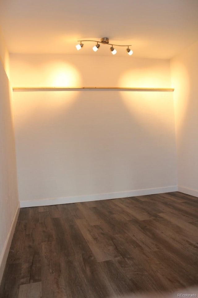 unfurnished room with dark hardwood / wood-style flooring and track lighting