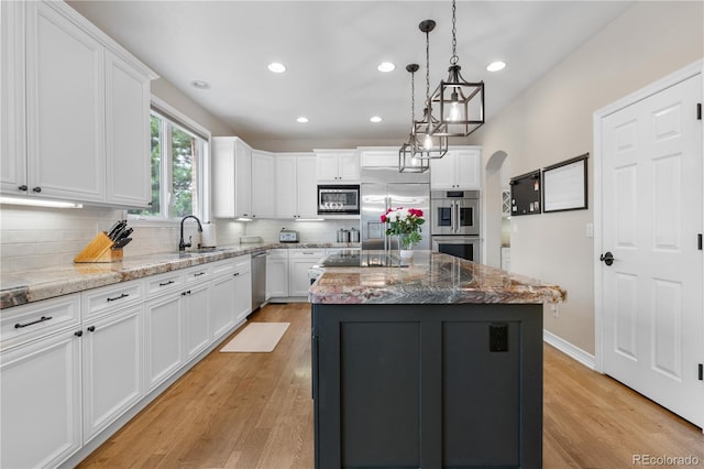 kitchen featuring built in appliances, backsplash, white cabinetry, and a sink