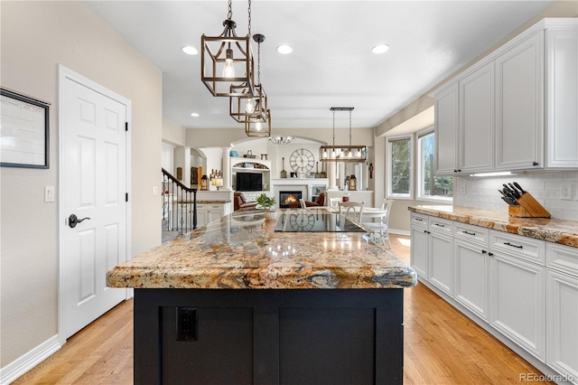 kitchen featuring light wood-style floors, recessed lighting, white cabinetry, and a warm lit fireplace