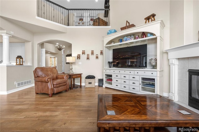 living area with baseboards, visible vents, wood finished floors, and a tile fireplace