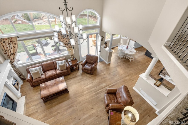 living area with wood finished floors, a high ceiling, a tiled fireplace, arched walkways, and a notable chandelier