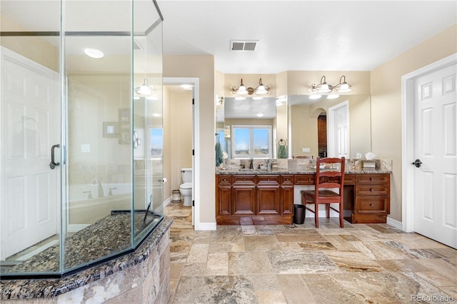 bathroom featuring vanity, toilet, stone tile floors, visible vents, and a stall shower